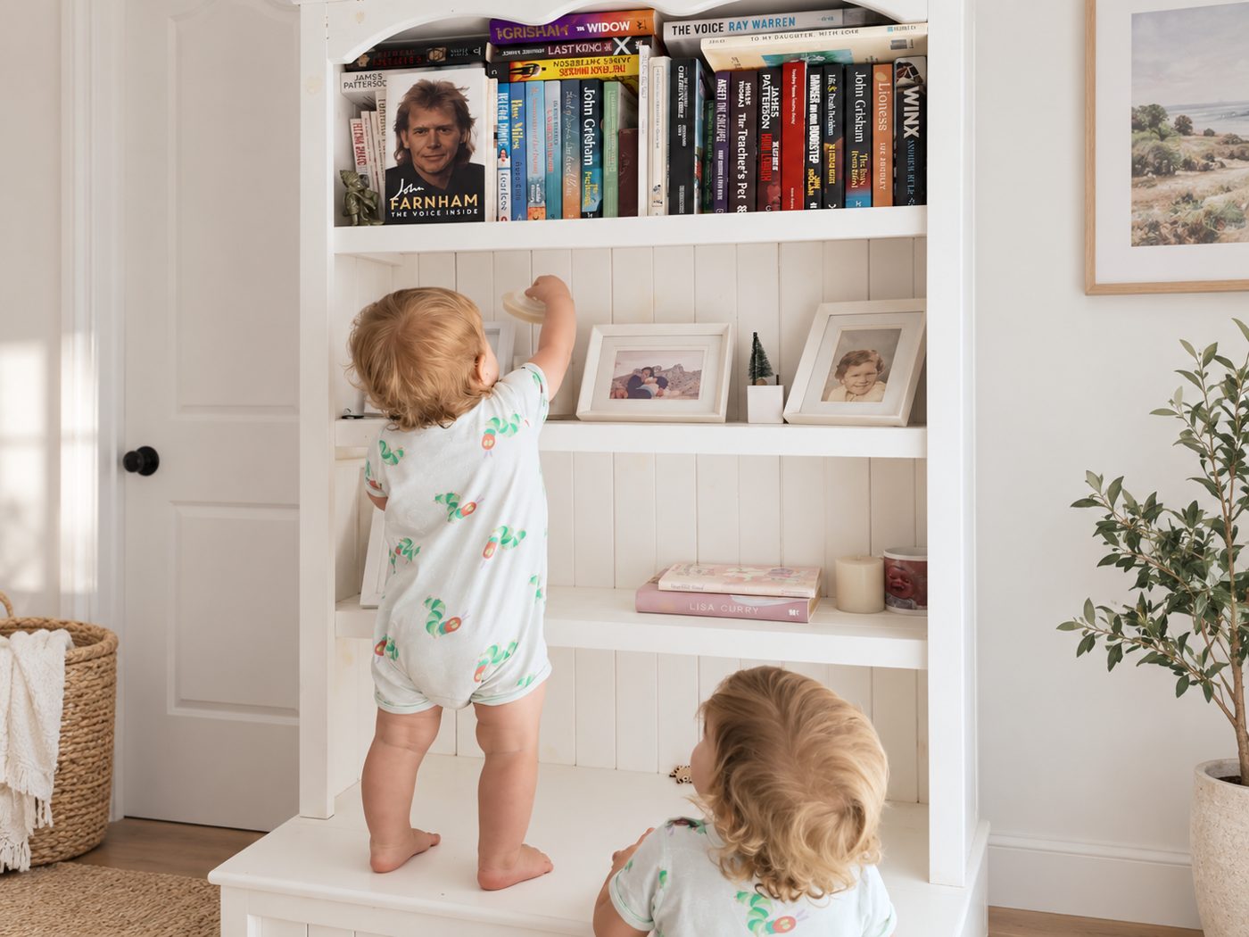 Two toddlers climbing a bookshelf, photographed from behind